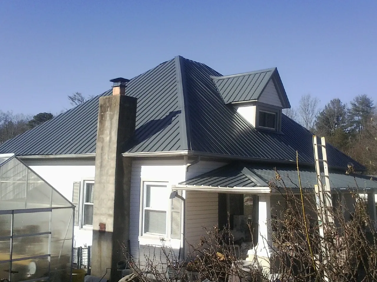 Dark blue standing seam metal roof on a white farmhouse with dormer — Slate & Tile Roof Repair by Roofing Brothers in Hannibal