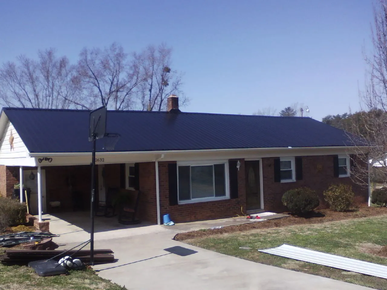 Finished dark blue metal roof on a brick ranch with a carport in Hannibal