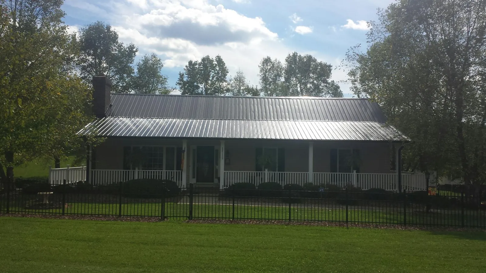 Gray metal roof on a brick ranch with a full width front porch — Gutter Guard Installation work by our crew in Hannibal